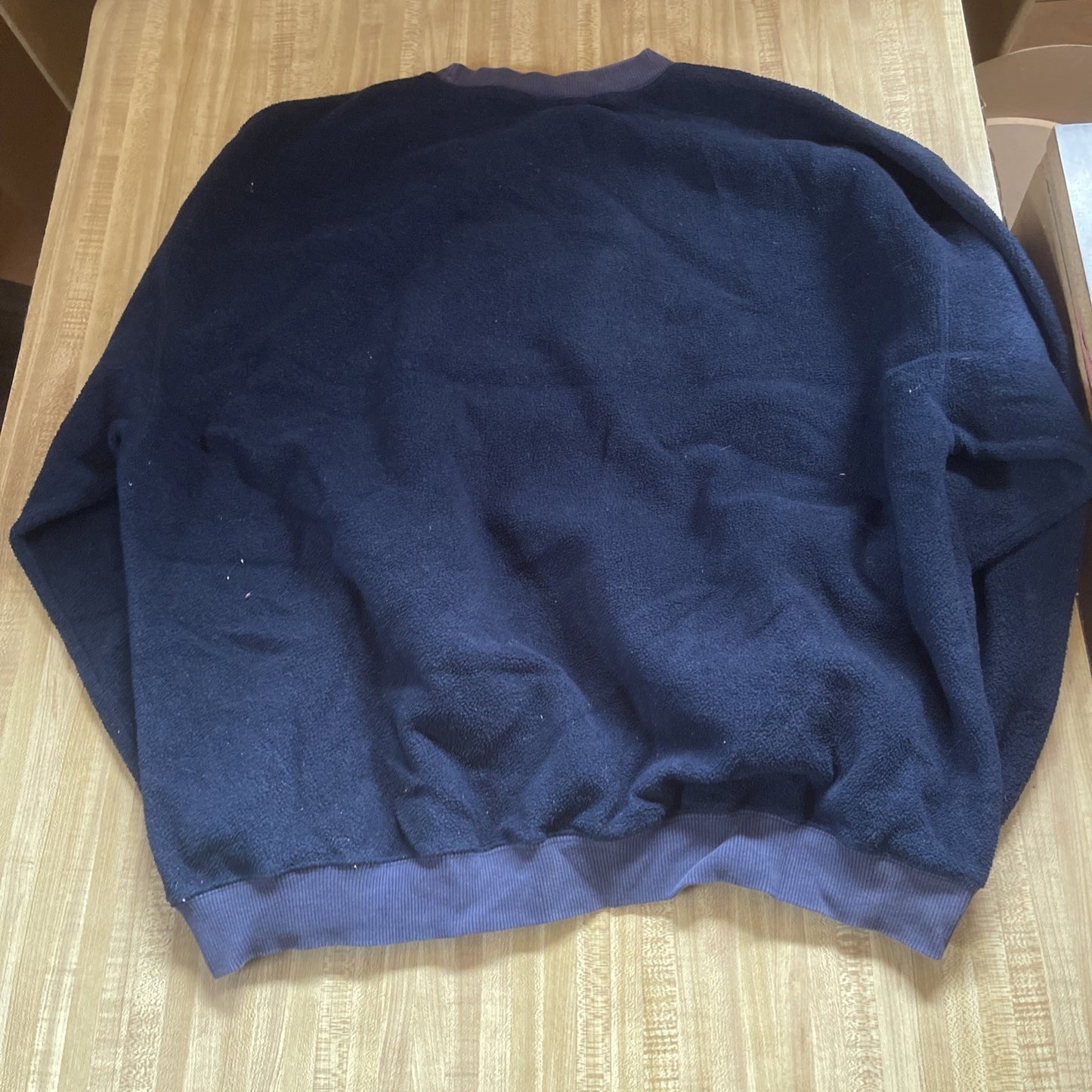 Back view of navy blue Disney 100 Acre Wood Friends sweater laid flat on wooden surface