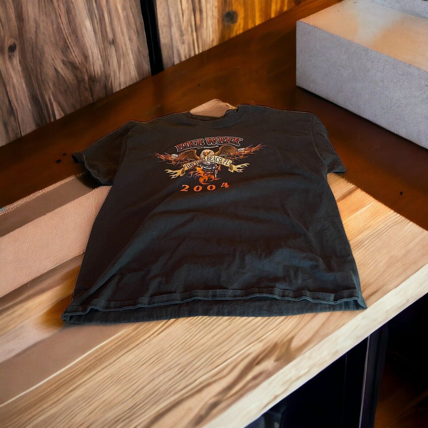 2004 Bike Week t shirt in black with flame graphic and event logo laid flat on wooden table