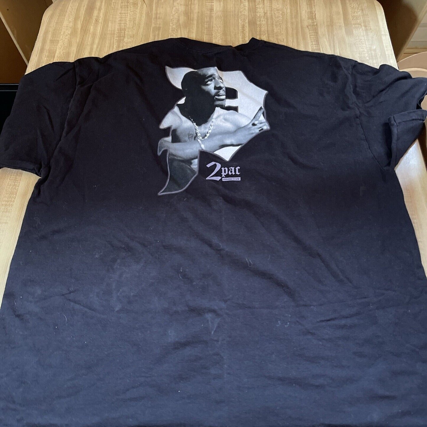 Black 2pac Primitive T Shirt featuring a grayscale graphic of Tupac Shakur on the back