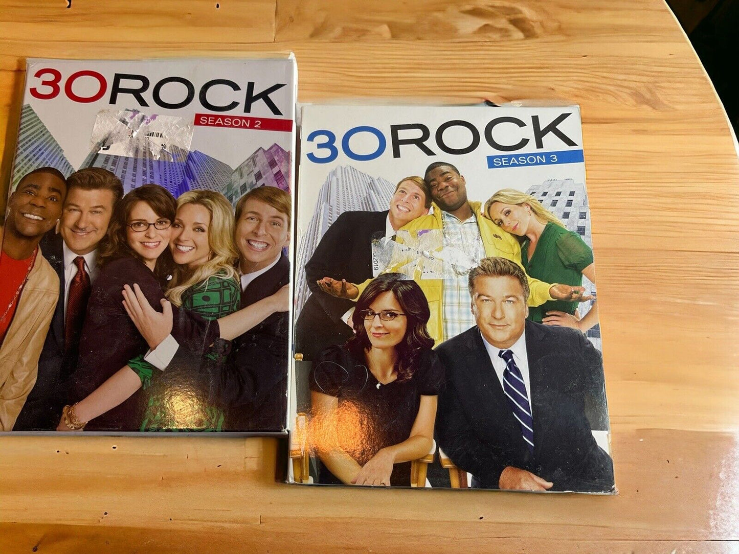 30 Rock comedy series DVD lot featuring season 2 and season 3 DVD cases on wooden table