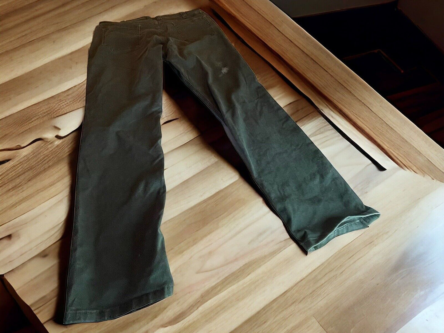5.11 tactical jeans for men in olive green laid flat on a wooden surface