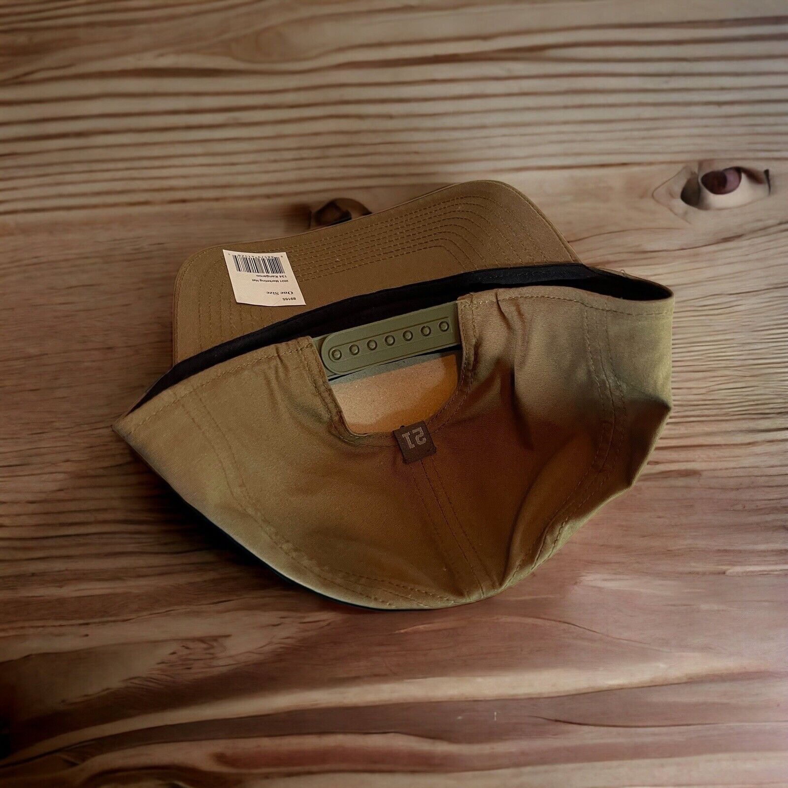 Tan 5.11 Tactical SnapBack hat with adjustable strap and black inner lining on wooden surface