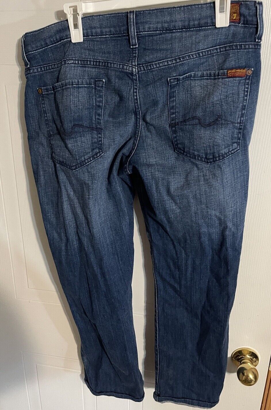 Back view of 7 for all mankind jeans in dark blue denim hanging on white hanger