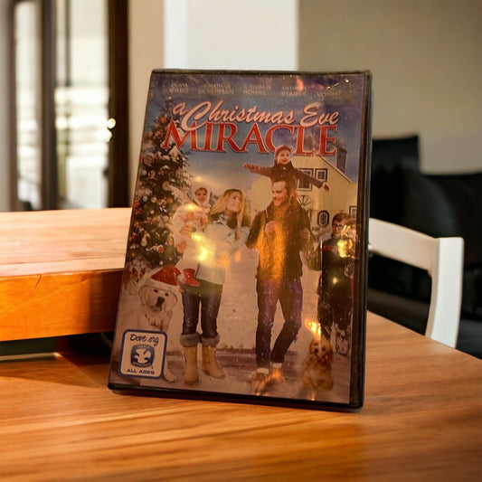A Christmas Eve Miracle DVD standing on a wooden table featuring a family with a Christmas tree and snowy background