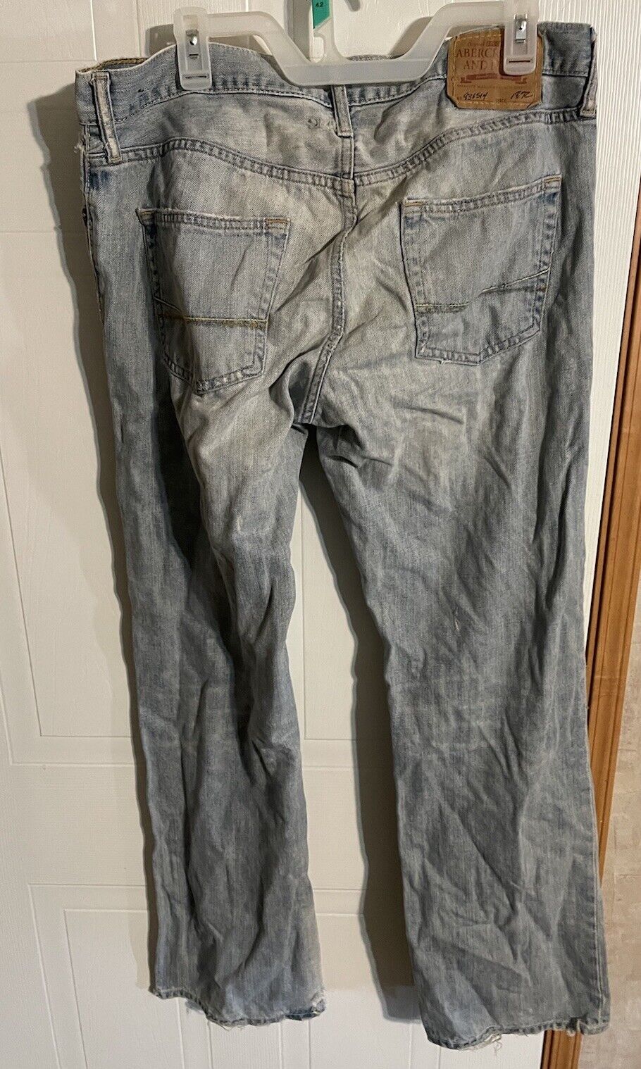 Abercrombie distressed jeans 32x34 in faded gray with frayed hems and back pockets hanging on a hanger