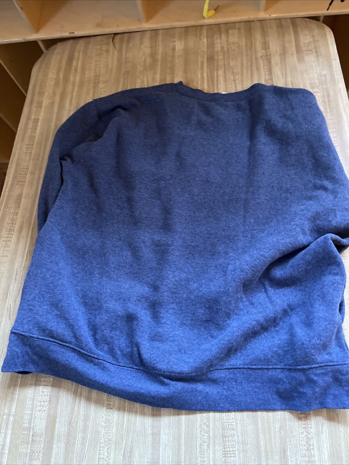 Blue AC Sport crewneck for men laid flat on a wooden surface showing soft fabric texture