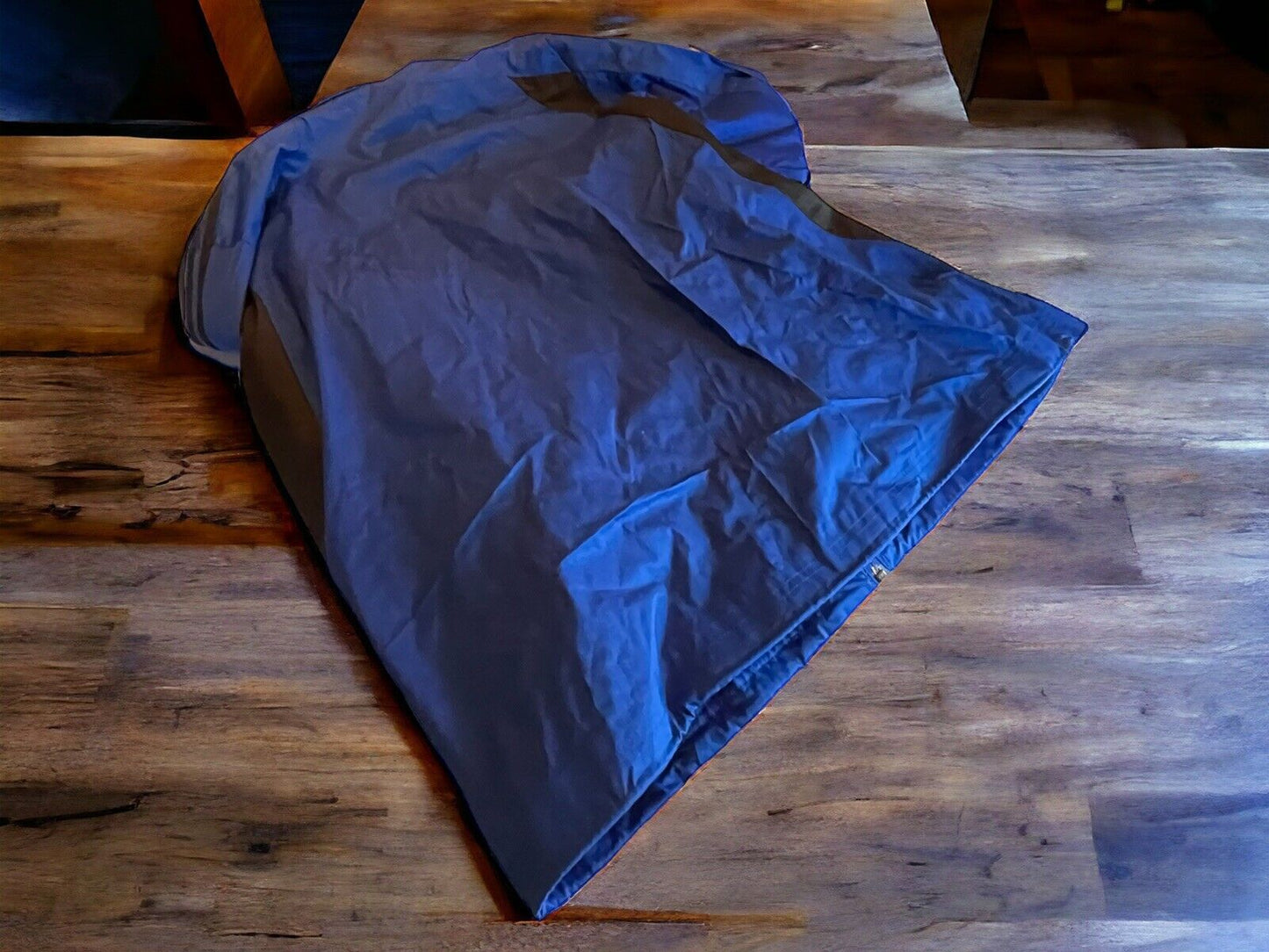 Large Adidas track jacket in dark color laid flat on wooden surface