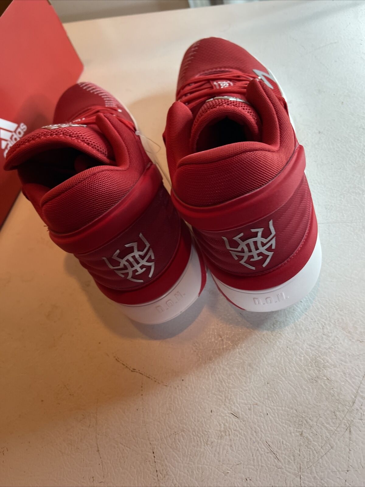 Pair of men's red adidas basketball shoes with cushioned ankle support and white sole