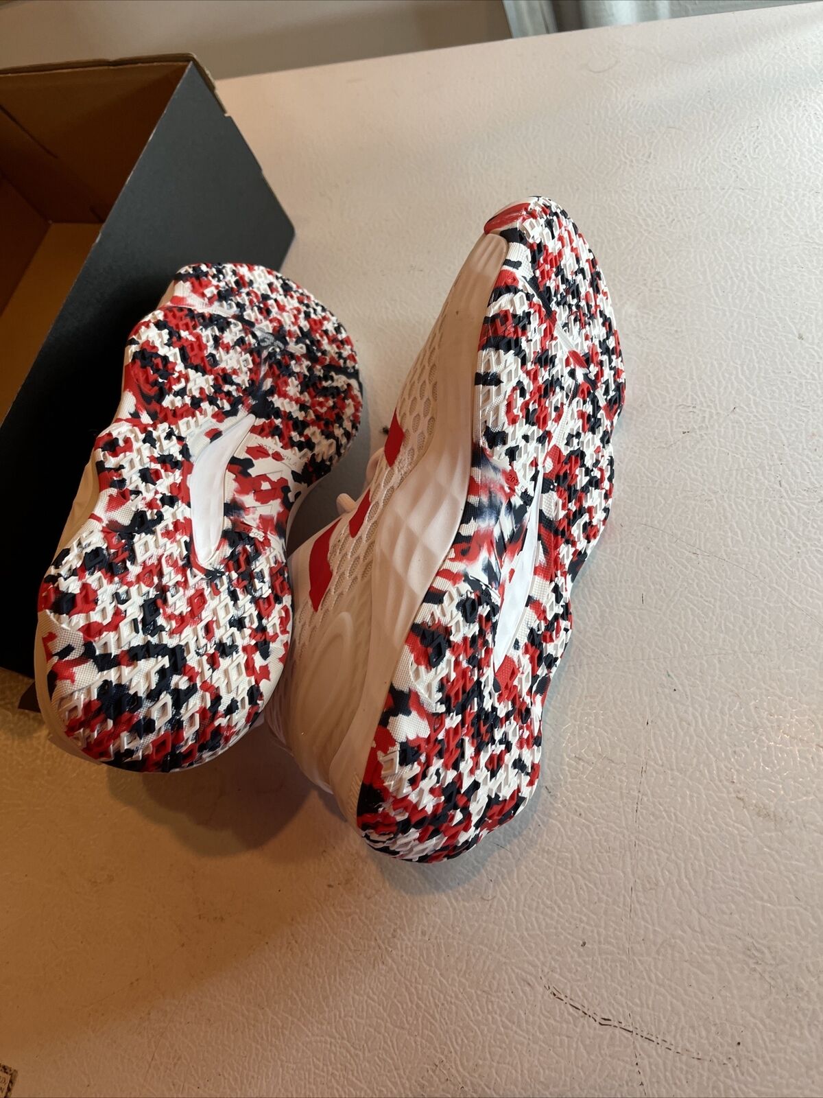 Adidas SM Exhibit A Team USA shoes with red white and black patterned soles displayed on table