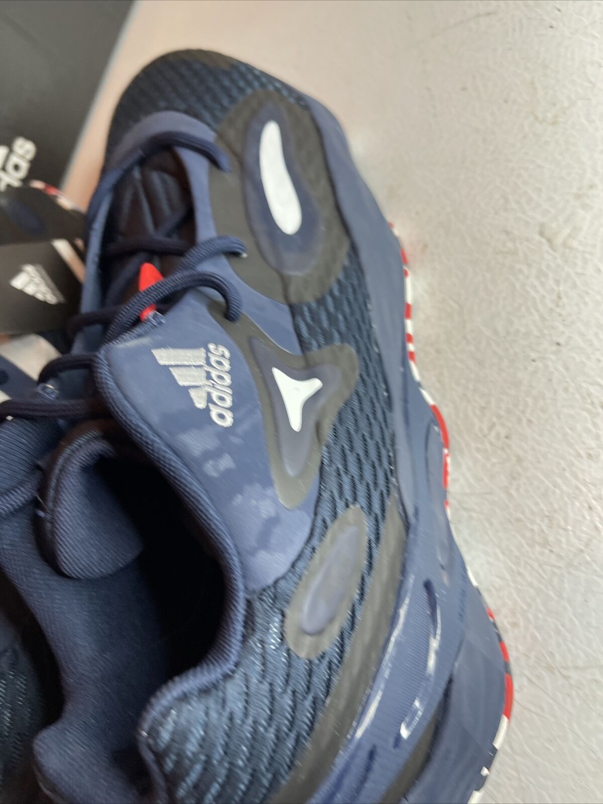 Close-up of Adidas SM Exhibit A Team USA shoes in navy blue with textured design and white Adidas logo