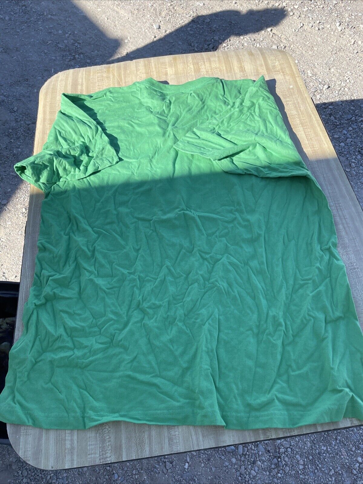 Green Akademiks 6XL t shirt laid flat on a table outdoors showing the full front side