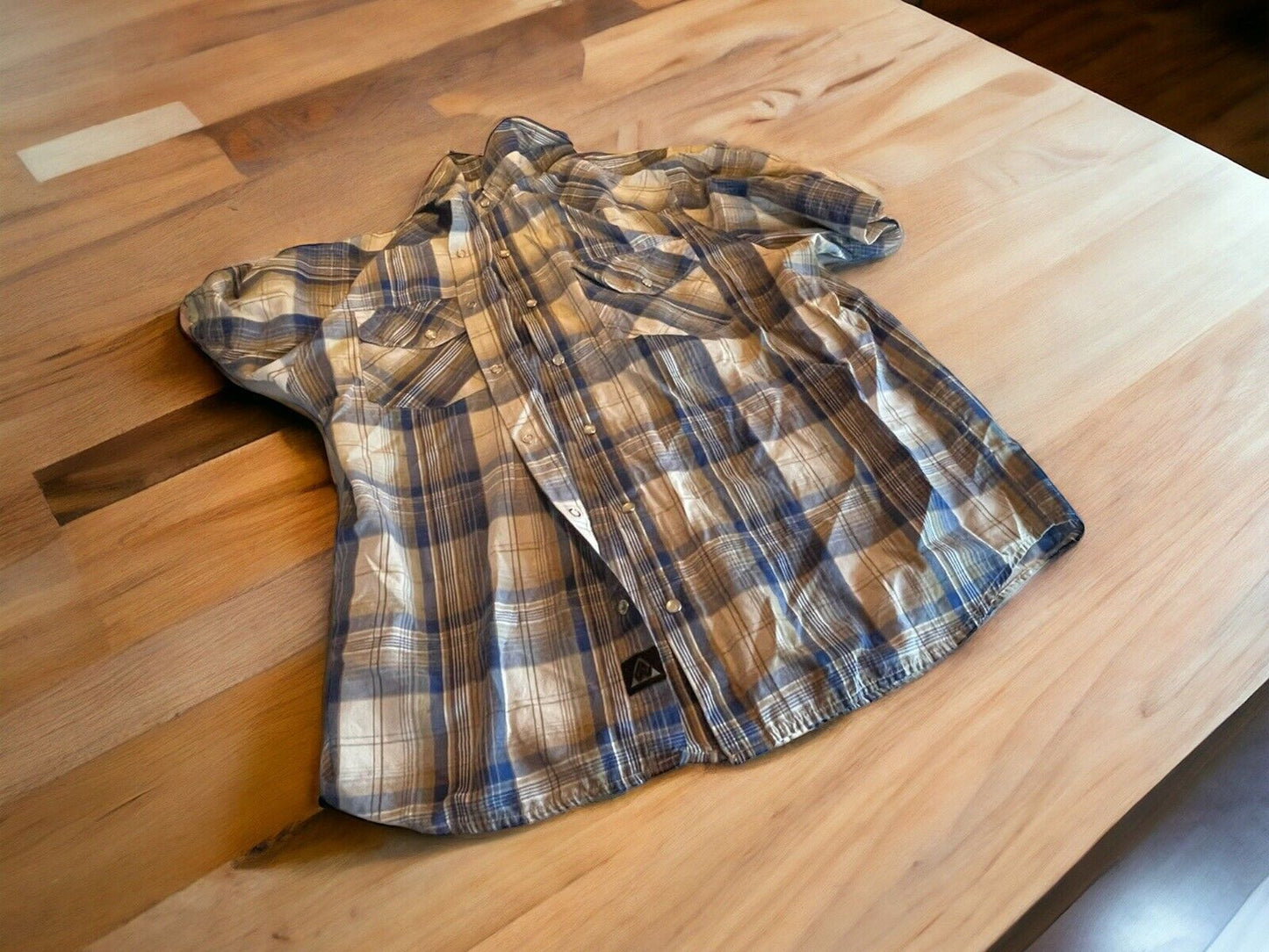 Americaware snap button shirt in blue and beige plaid pattern laid flat on wooden table