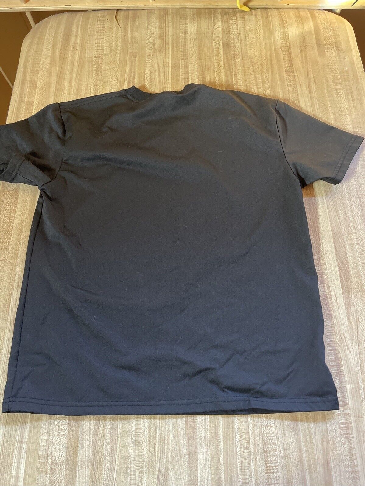 Black plain back view of anime graphic t shirt medium laid flat on wooden surface