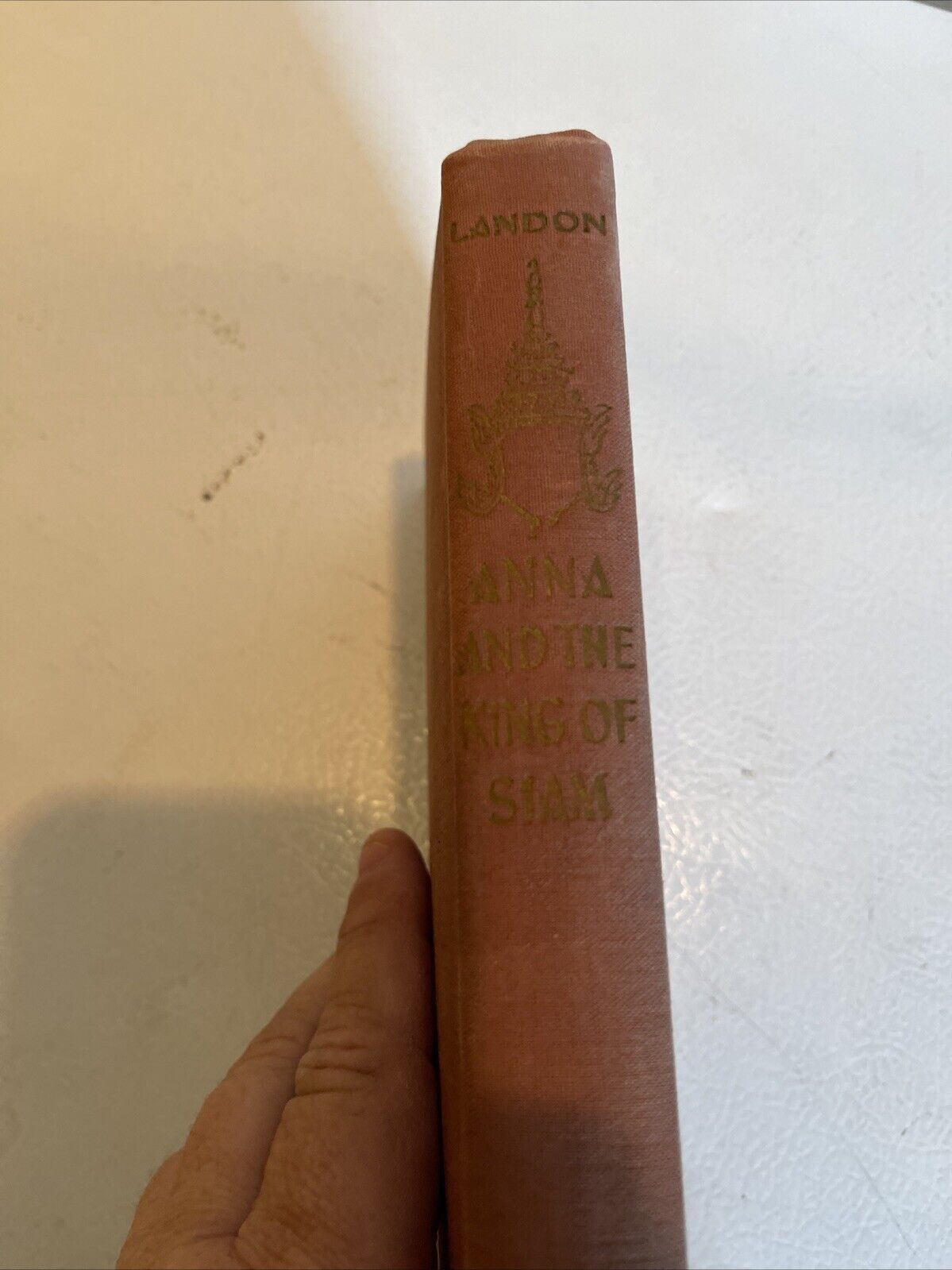 Spine of Anna and the King of Siam first edition book with embossed gold lettering held by hand