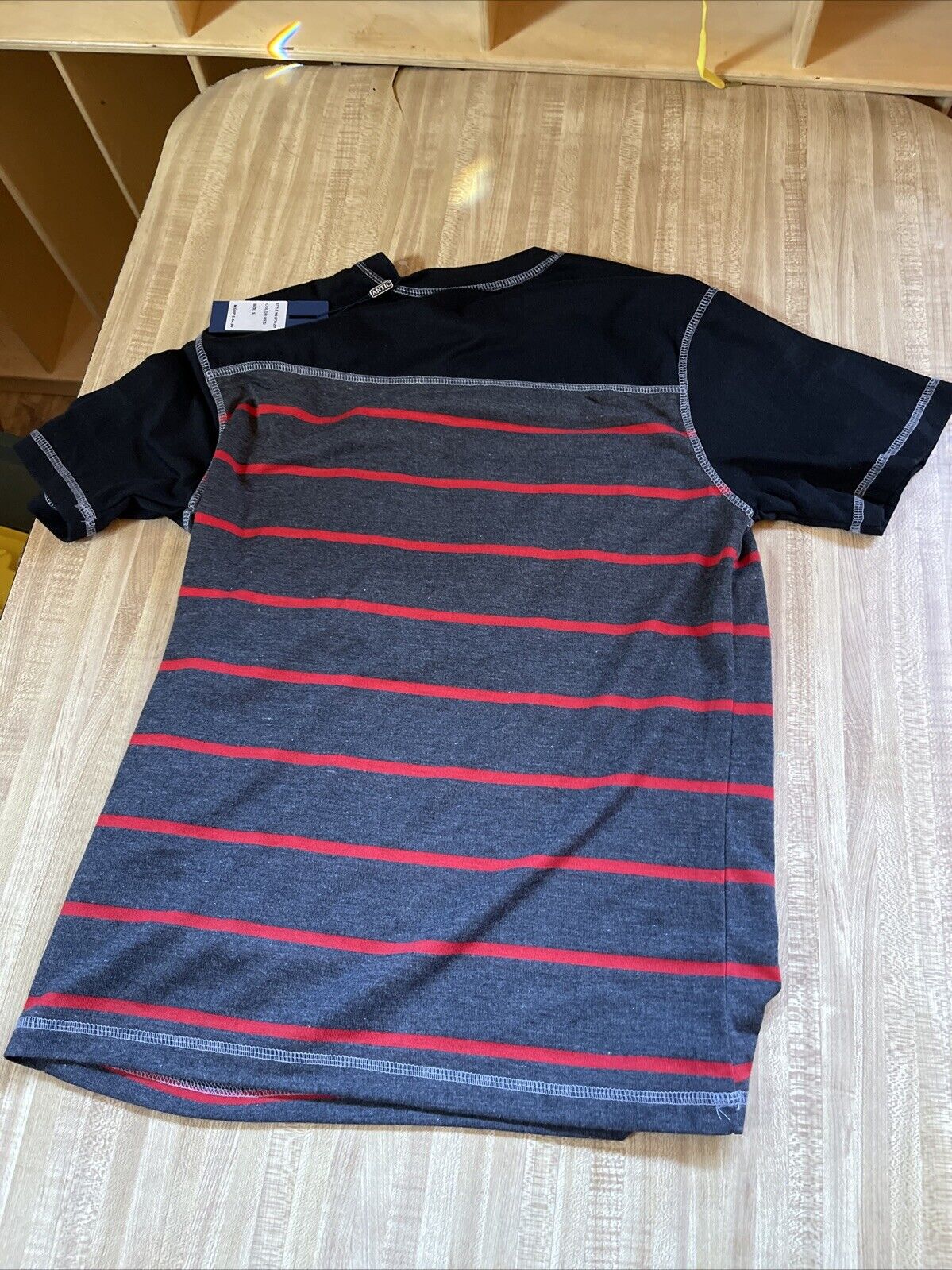 Small antic shirt for men with black sleeves and gray body featuring red horizontal stripes