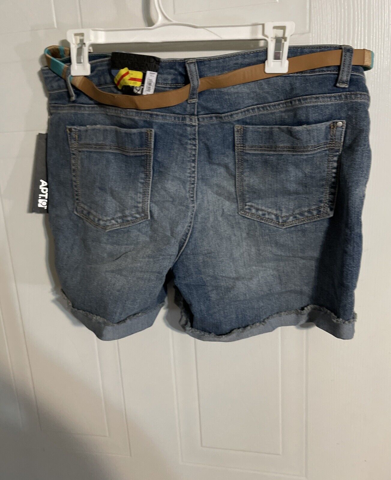 Apt 9 denim shorts in blue with back pockets and frayed hems hanging on a white hanger