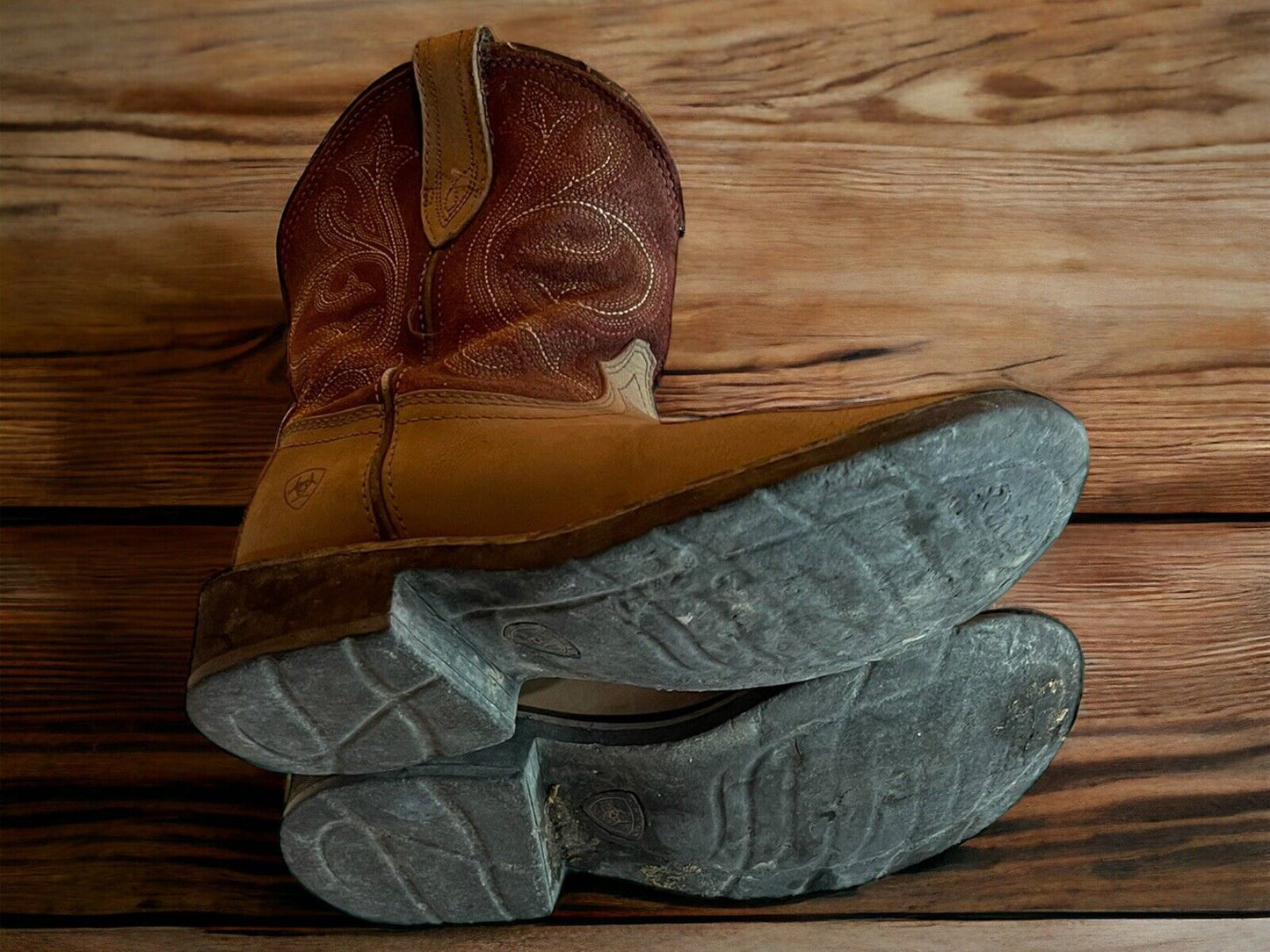 Ariat Fatbaby Heritage boots in brown leather with detailed stitching and worn soles on a wooden surface