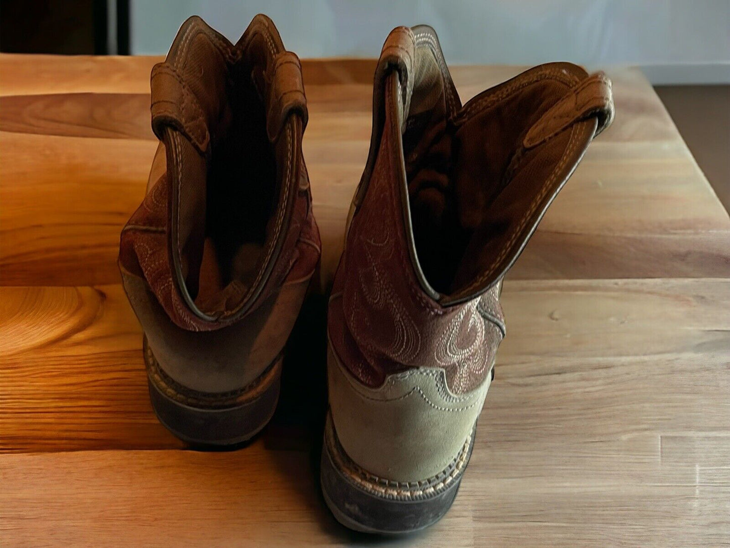 Pair of Ariat Fatbaby Heritage boots in brown leather with detailed stitching on wooden surface