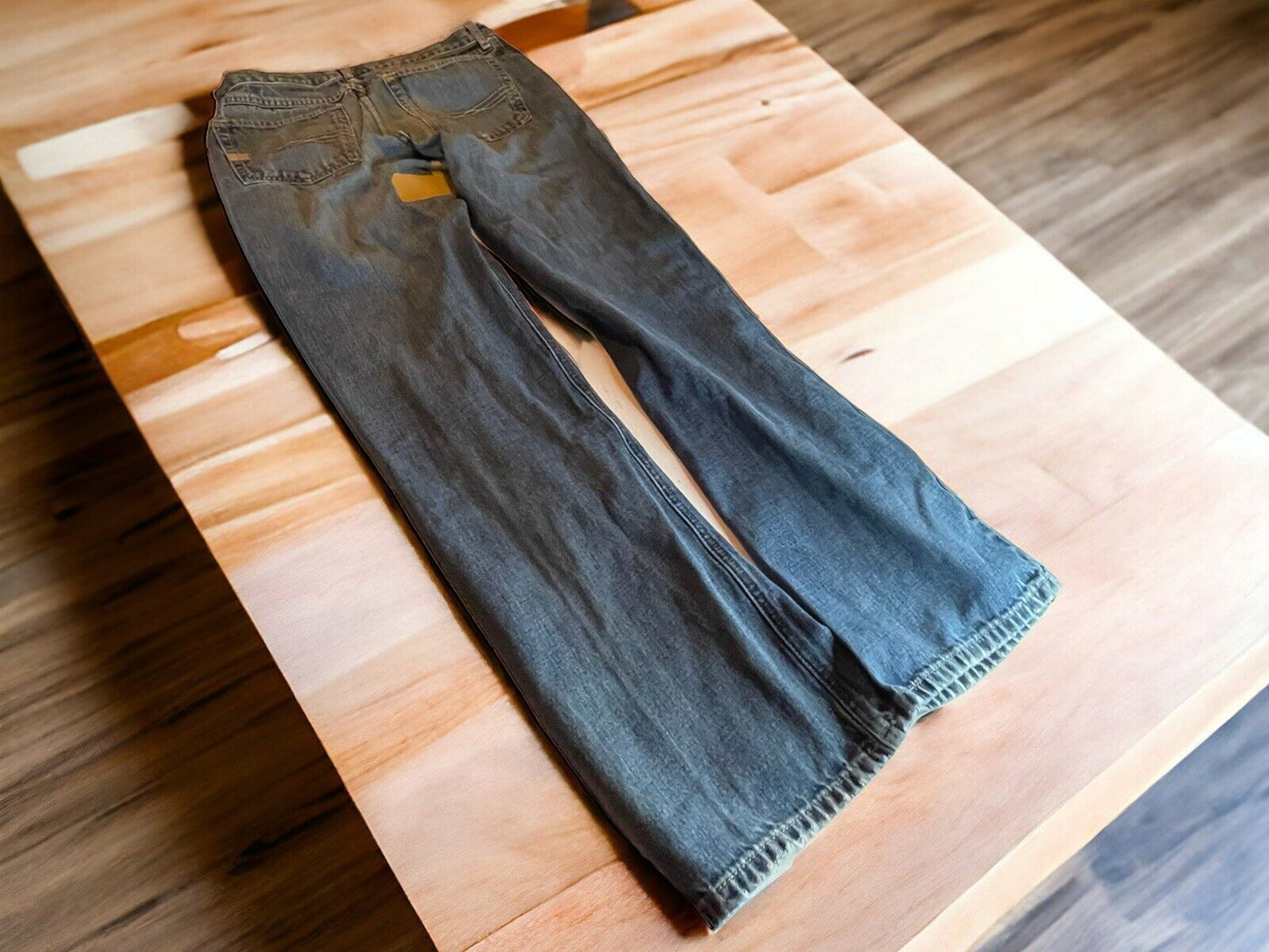 Ariat M4 jeans 33x34 in faded blue denim laid flat on wooden table with detailed stitching