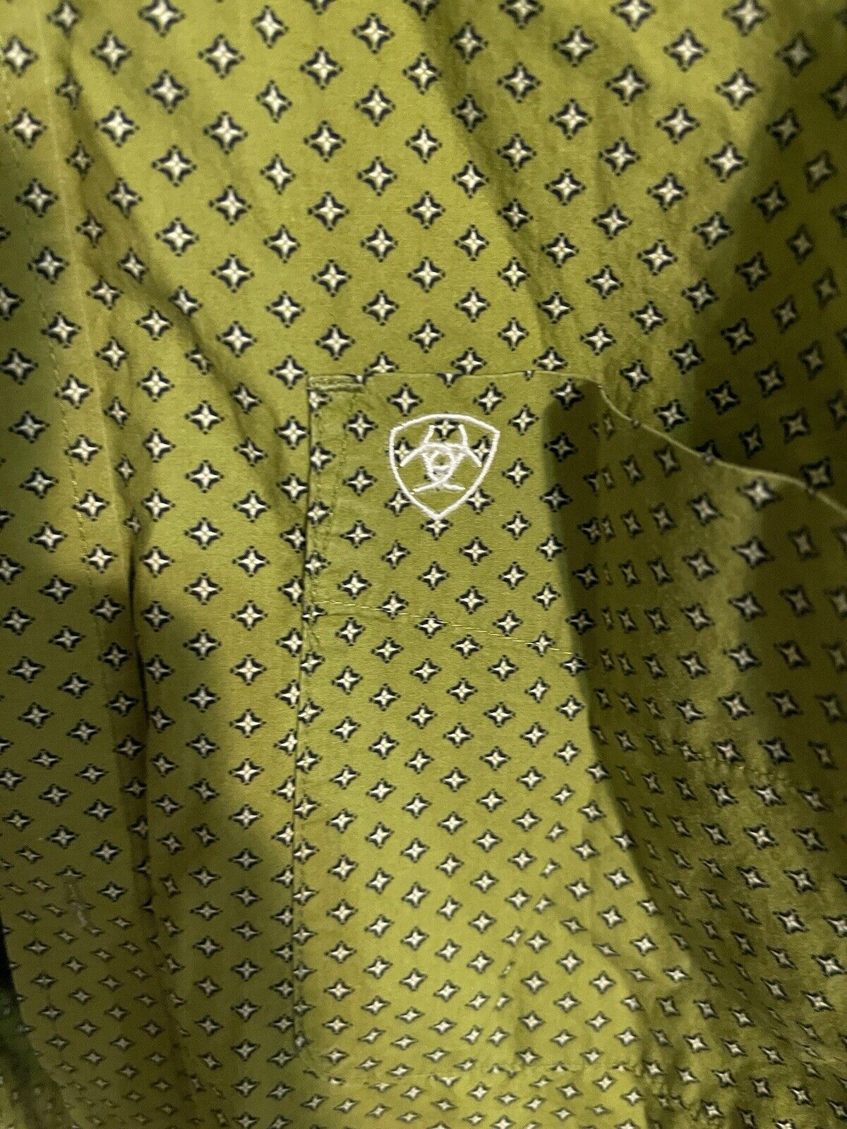 Close-up of Ariat men's medium shirt in green with small black and white diamond pattern and Ariat logo on pocket