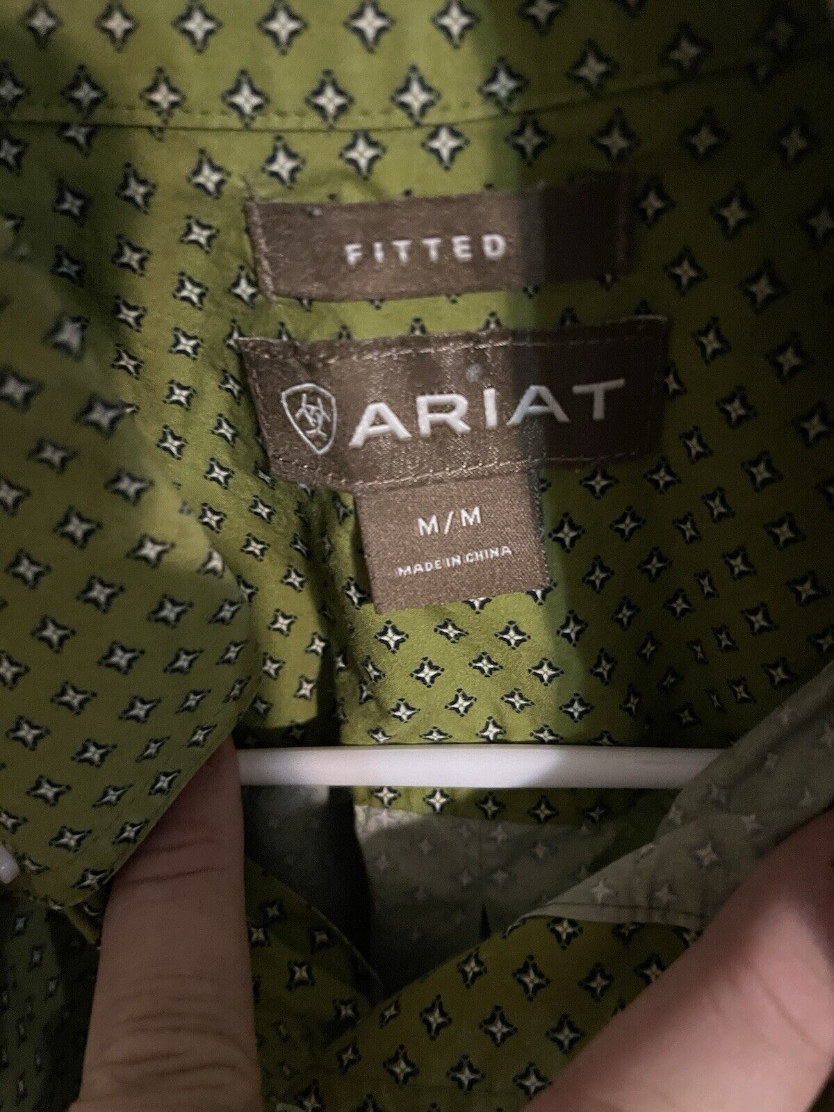 Close-up of Ariat men's medium shirt green fabric with white star pattern and fitted label