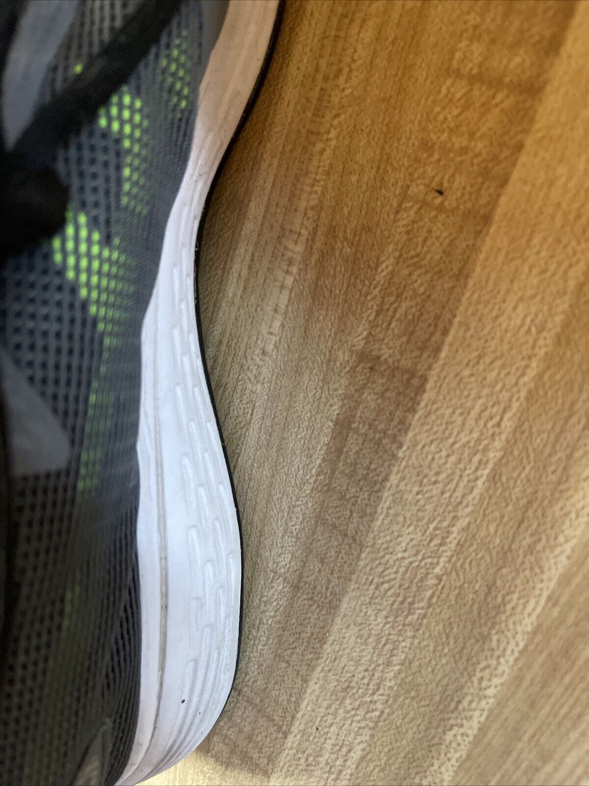 Close-up side view of ASICS Patriot 10 men’s running shoes with black mesh upper and white sole