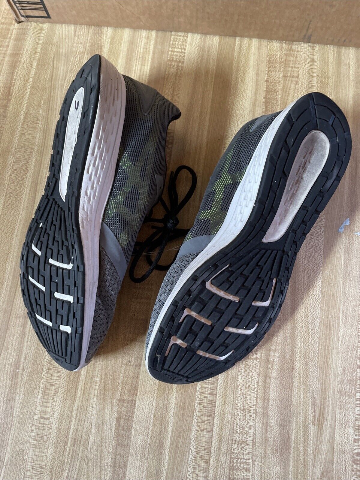Bottom view of ASICS Patriot 10 men’s running shoes showing black rubber soles and cushioning