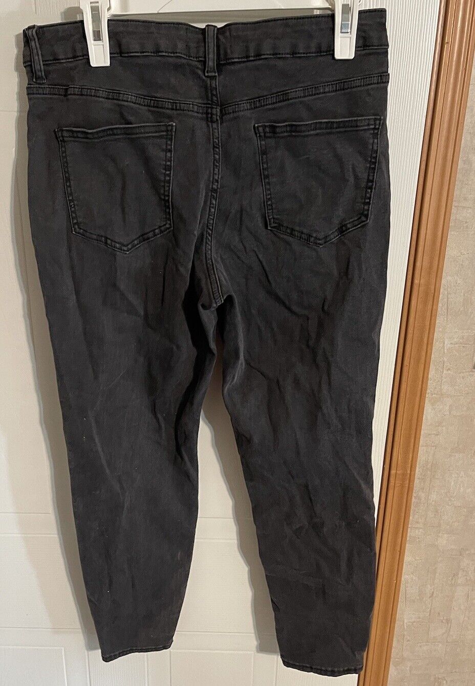 Black ASOS Design jeans men hanging showing back pockets and stitching details