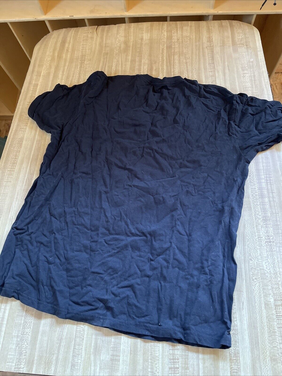 Black Attack on Titan final season t shirt laid flat on wooden surface showing back side