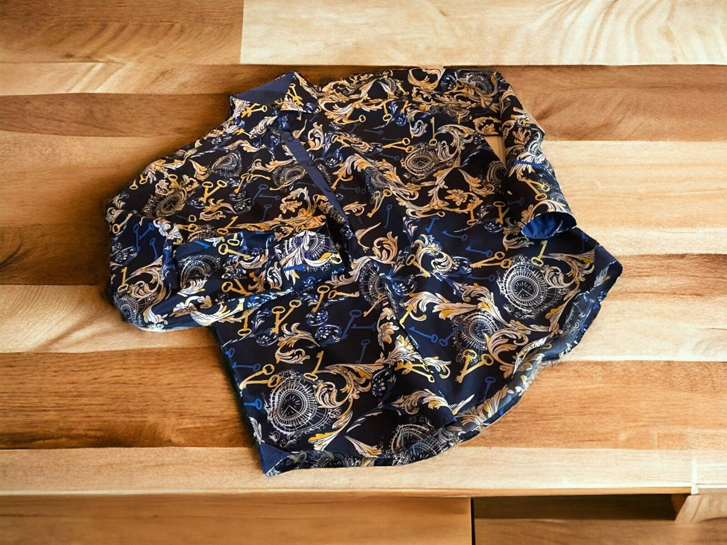 Azaro Uomo shirt medium with intricate gold and black baroque pattern laid on wooden surface