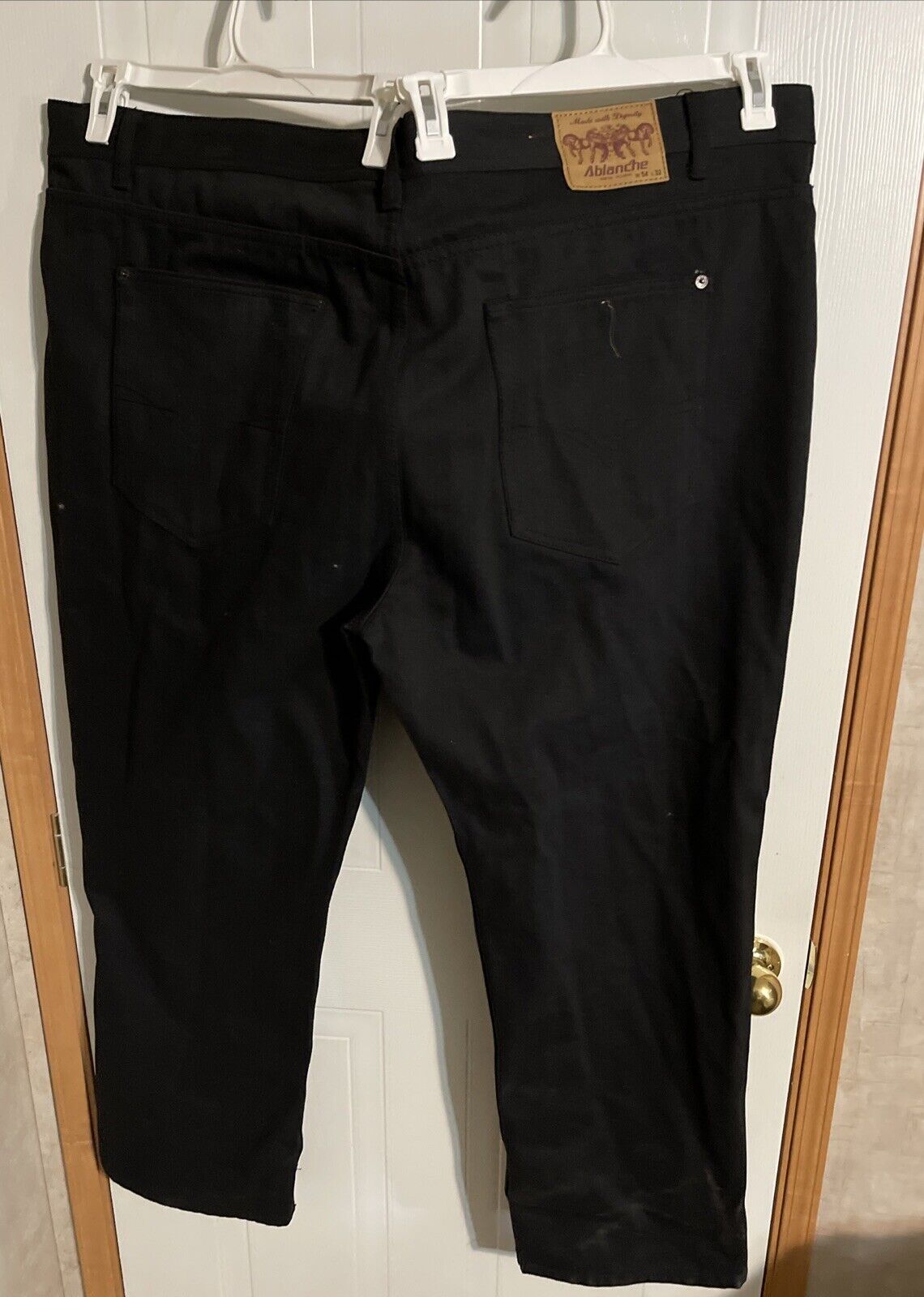 Big and tall black jeans men hanging on white hangers showing back pockets and waistband label