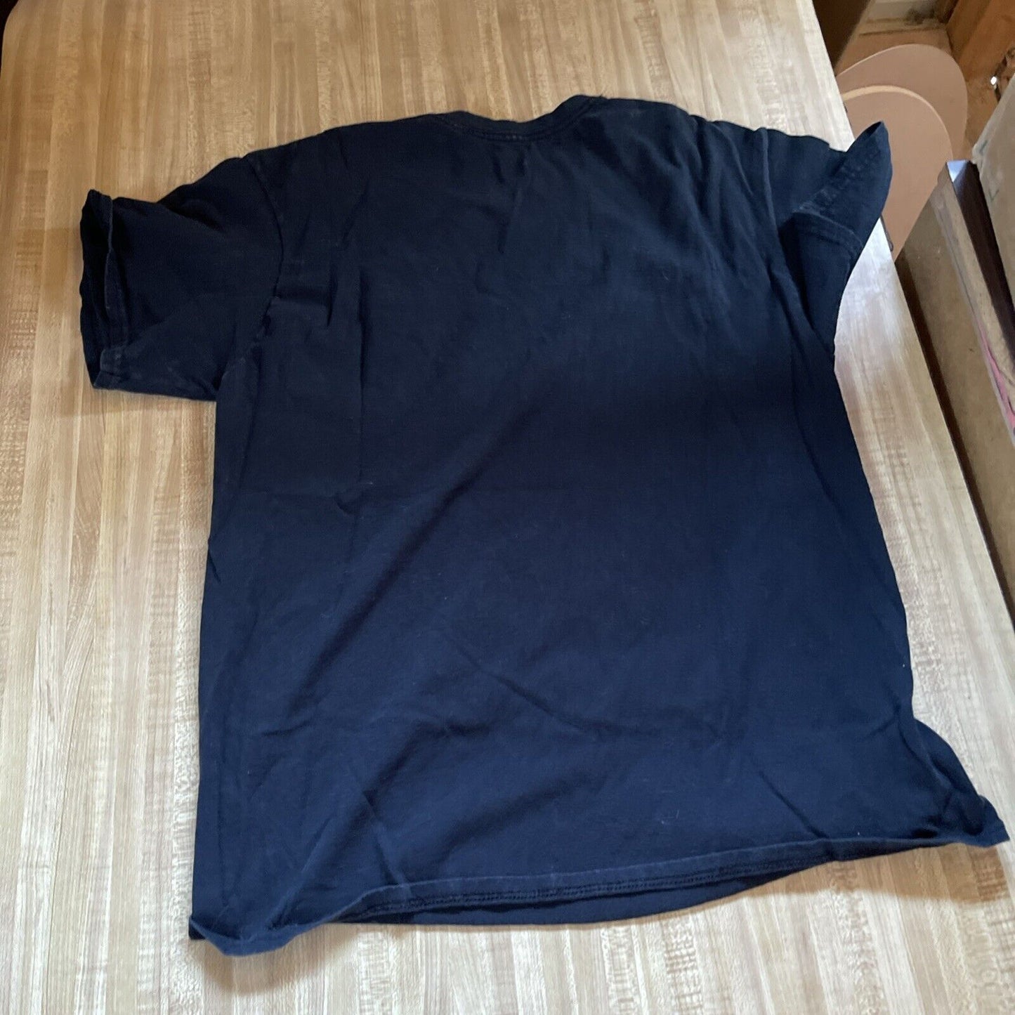 Black Bob Marley Legend T Shirt laid flat on a wooden surface showing the back side