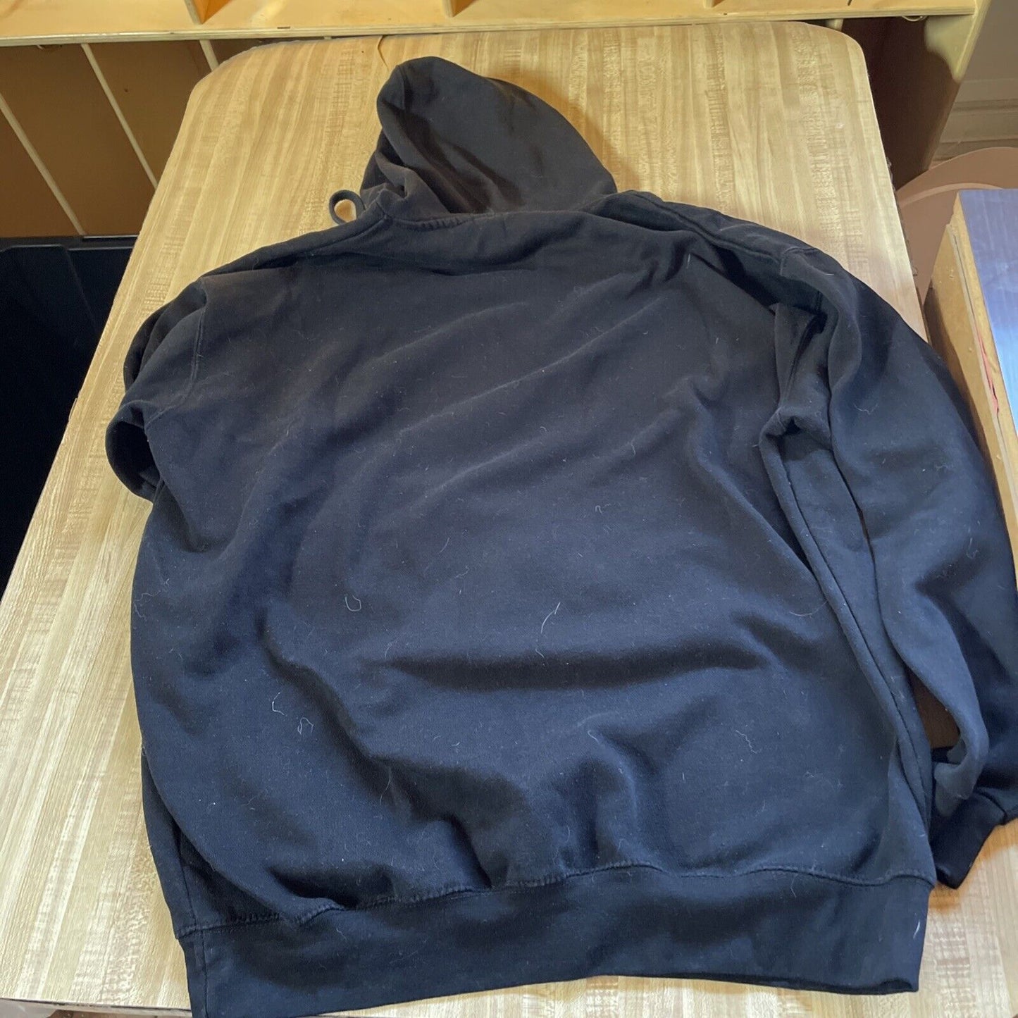 Black Dallas Cowboys hoodie 2XL laid flat on a wooden table showing the back side