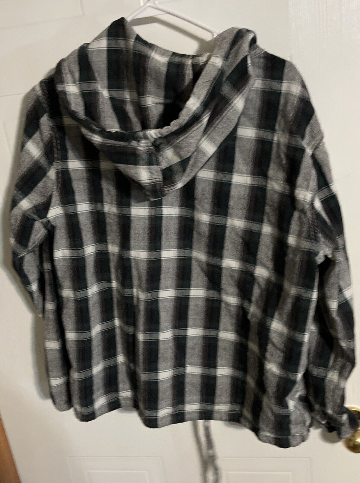 Black and white checkered Gramicci flannel hoodie hanging on a hanger with hood visible