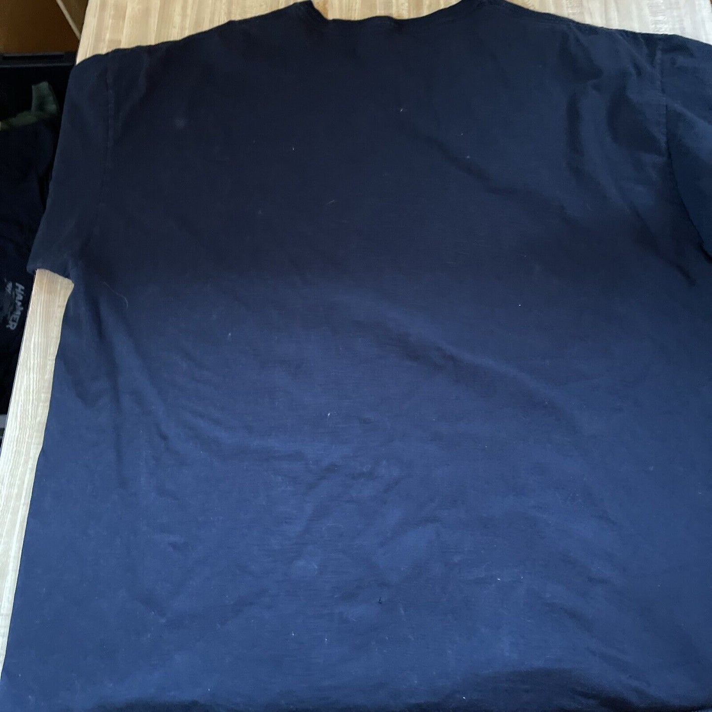Back view of a black horror movie graphic tee 3XL laid flat on a wooden surface