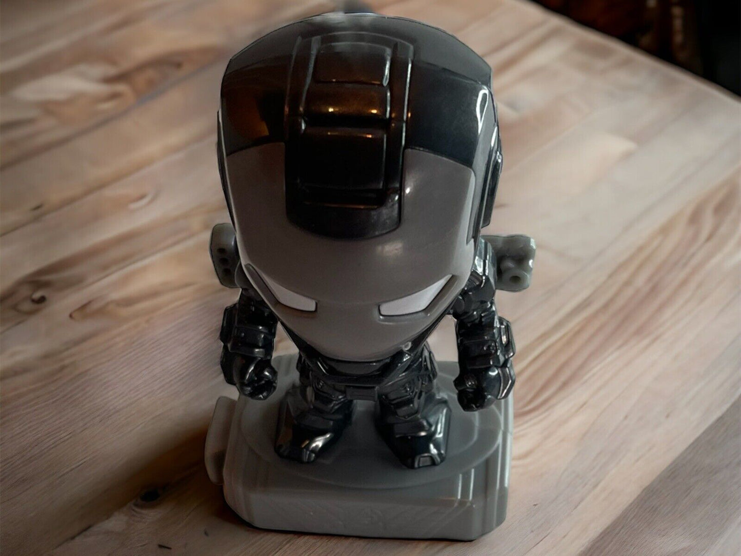 Marvel action figure toy of a black and gray armored hero standing on a gray base on a wooden surface