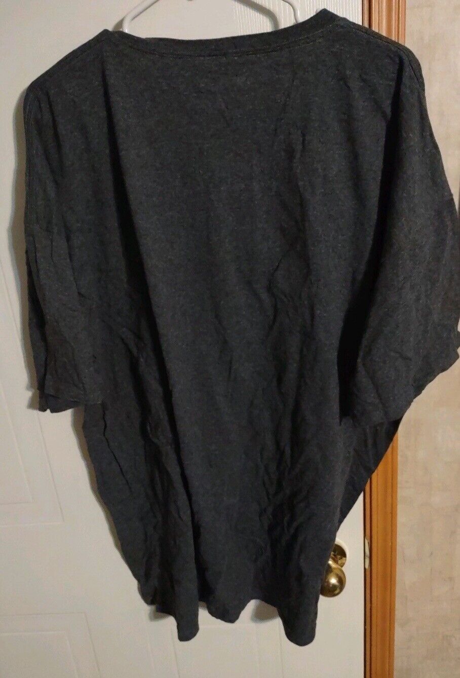 1118 Emporium mens black casual t shirt 3XL hanging on a hanger against door and wall background