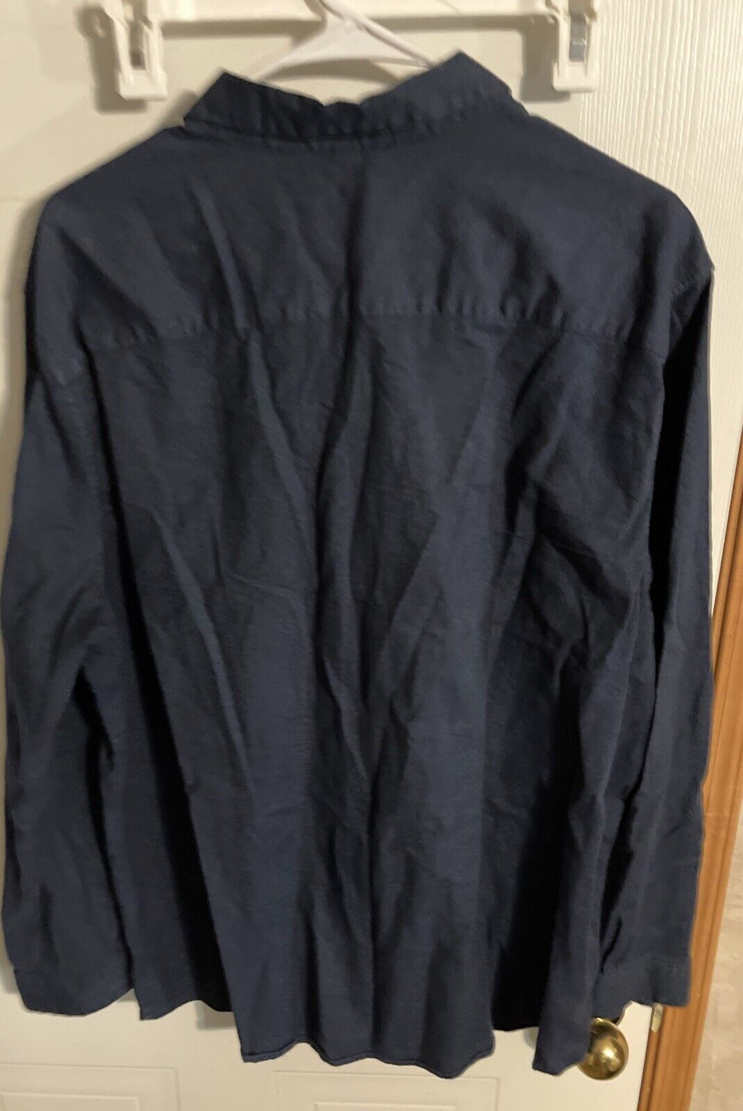 Men's navy button up shirt XL hanging on white hanger with long sleeves and button collar