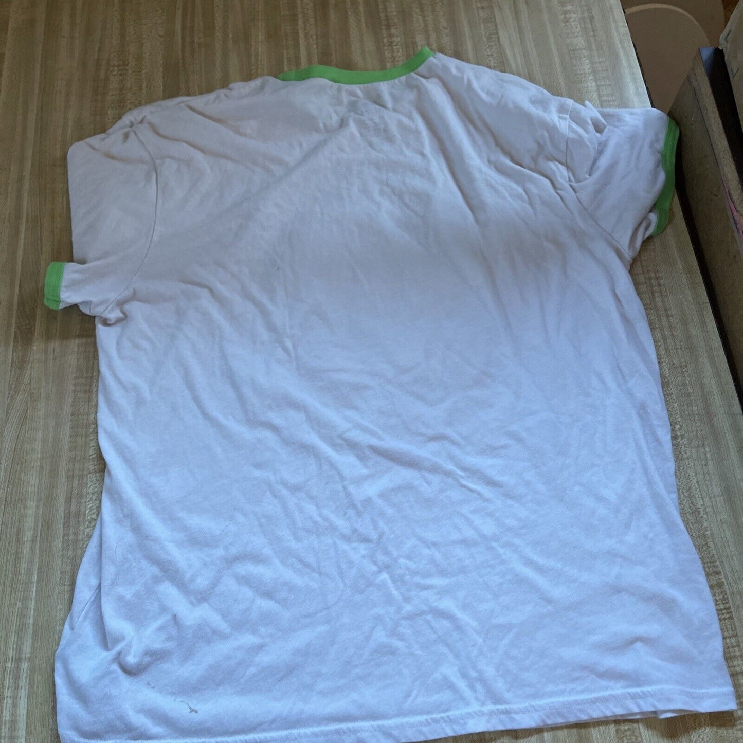 White Rick and Morty ringer t shirt XL with green collar and sleeve edges laid flat on wooden surface