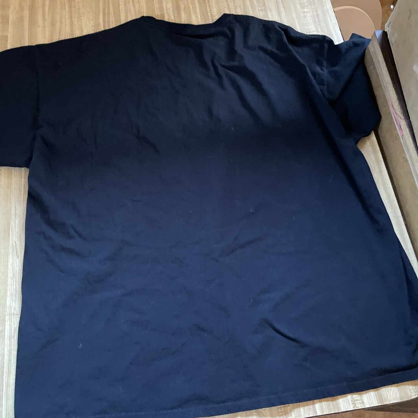 Black plain back view of horror fan gift shirt 3XL laid flat on wooden surface