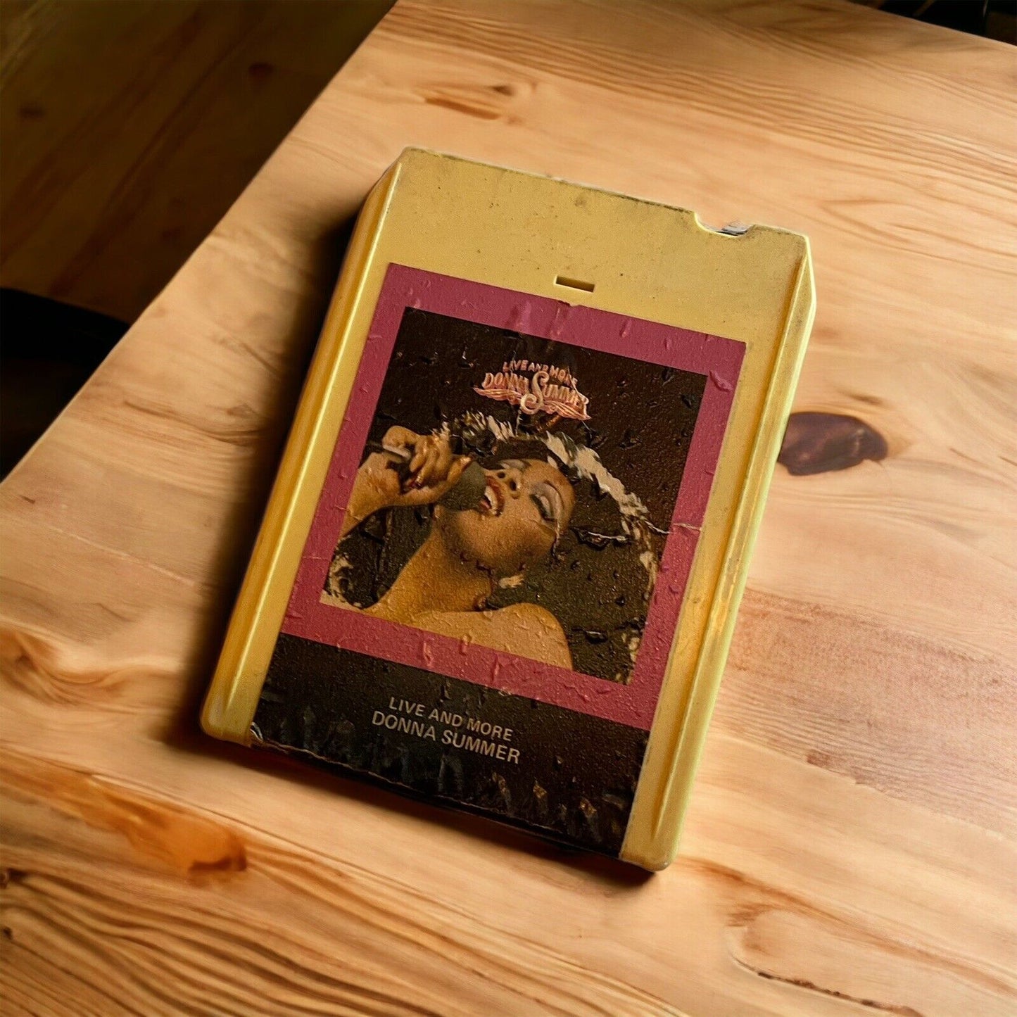 Vintage Live and More tape featuring Donna Summer in yellow 8-track cartridge on wood surface