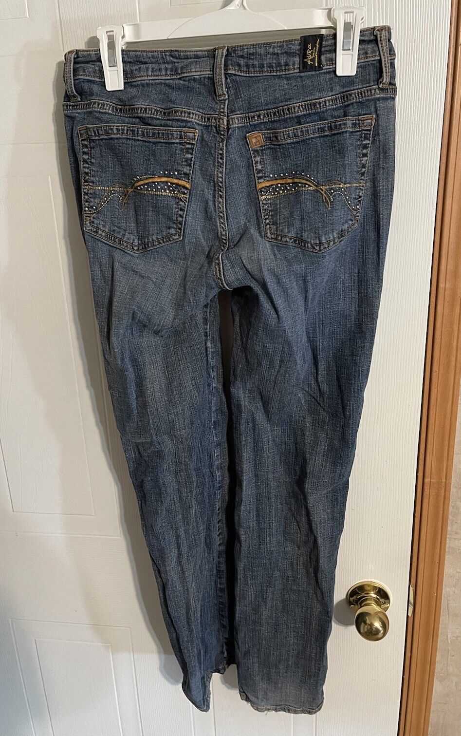 Back view of women's short length jeans in dark wash denim hanging on a white hanger