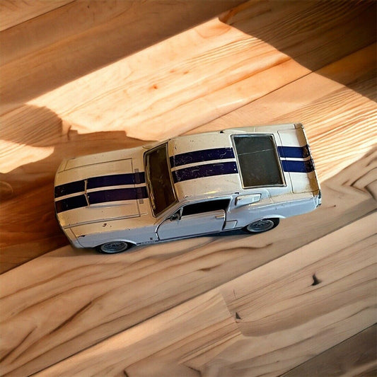 1 88 scale Shelby collectible model car in white with blue racing stripes on wooden surface