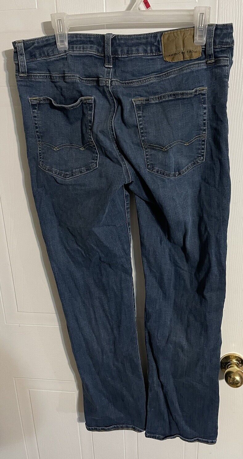 Back view of American Eagle bootcut jeans in dark blue denim hanging on clear hanger