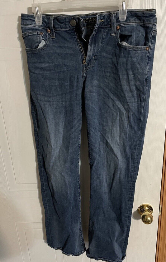 American Eagle bootcut jeans in dark blue denim hanging on a hanger with visible front pockets and button closure