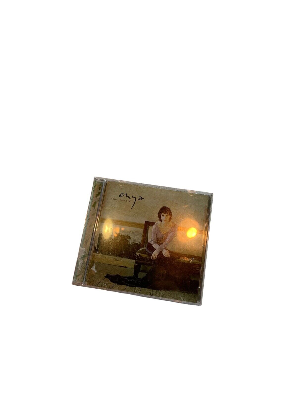 A Day Without Rain Enya CD album cover featuring Enya sitting with a soft sunset background