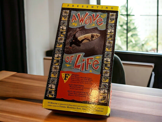 A Wave Of Life VHS tape featuring surfing scenes with colorful cover art on wooden table