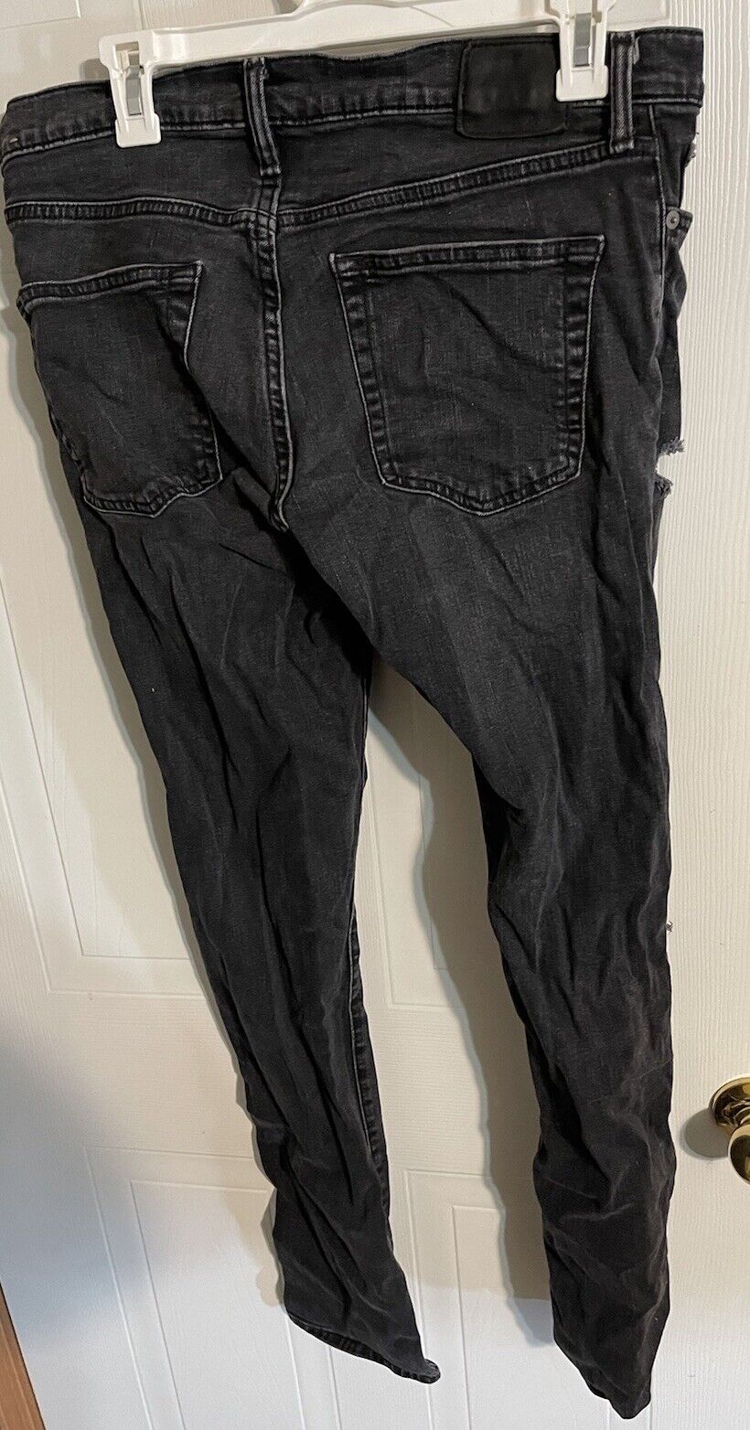 Black Abercrombie Fitch Langdon slim jeans hanging on a white hanger showing back pockets and slim fit design