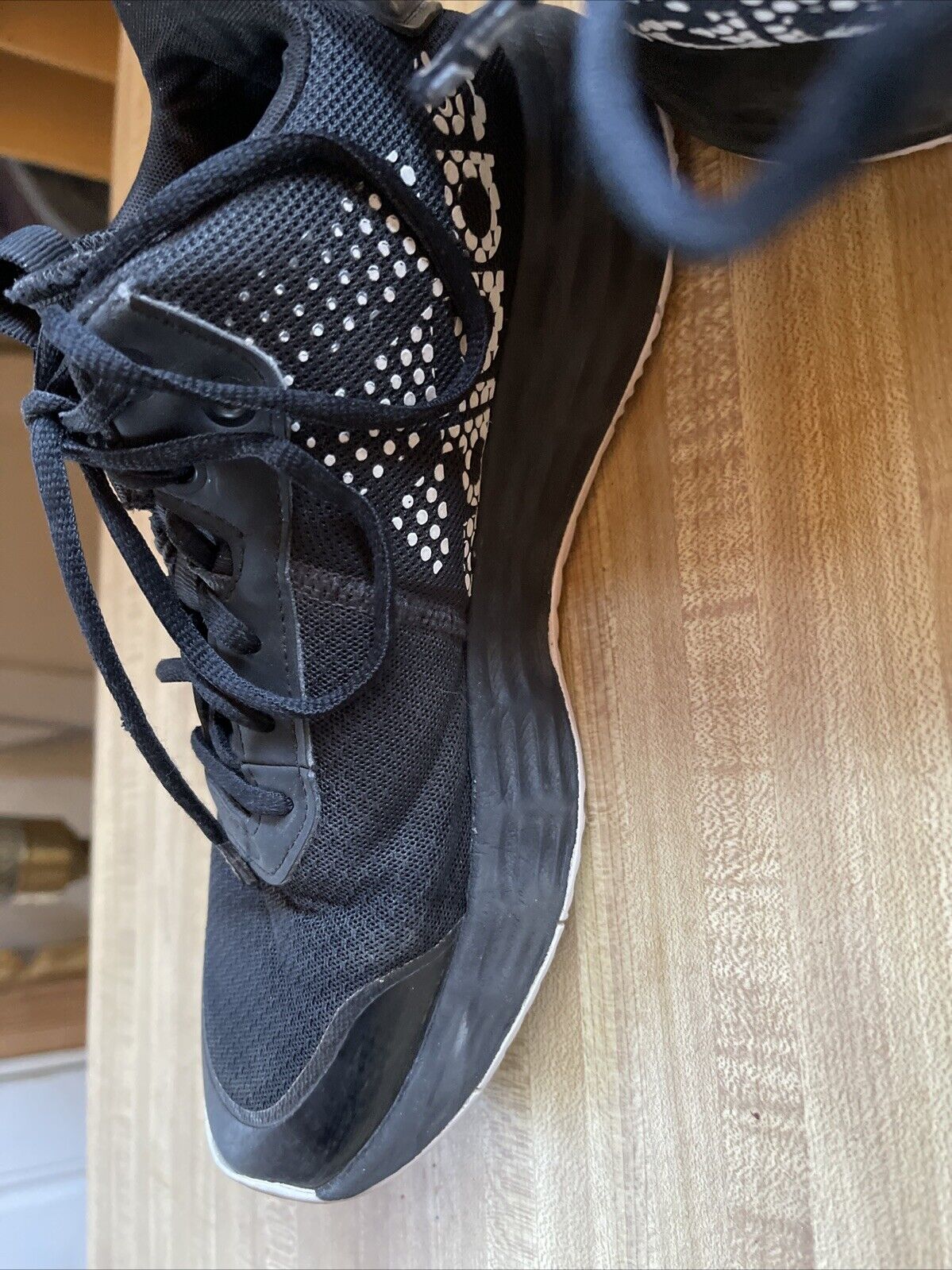 Black adidas lightmotion size 11 athletic shoe with mesh upper and cushioned sole on wooden surface