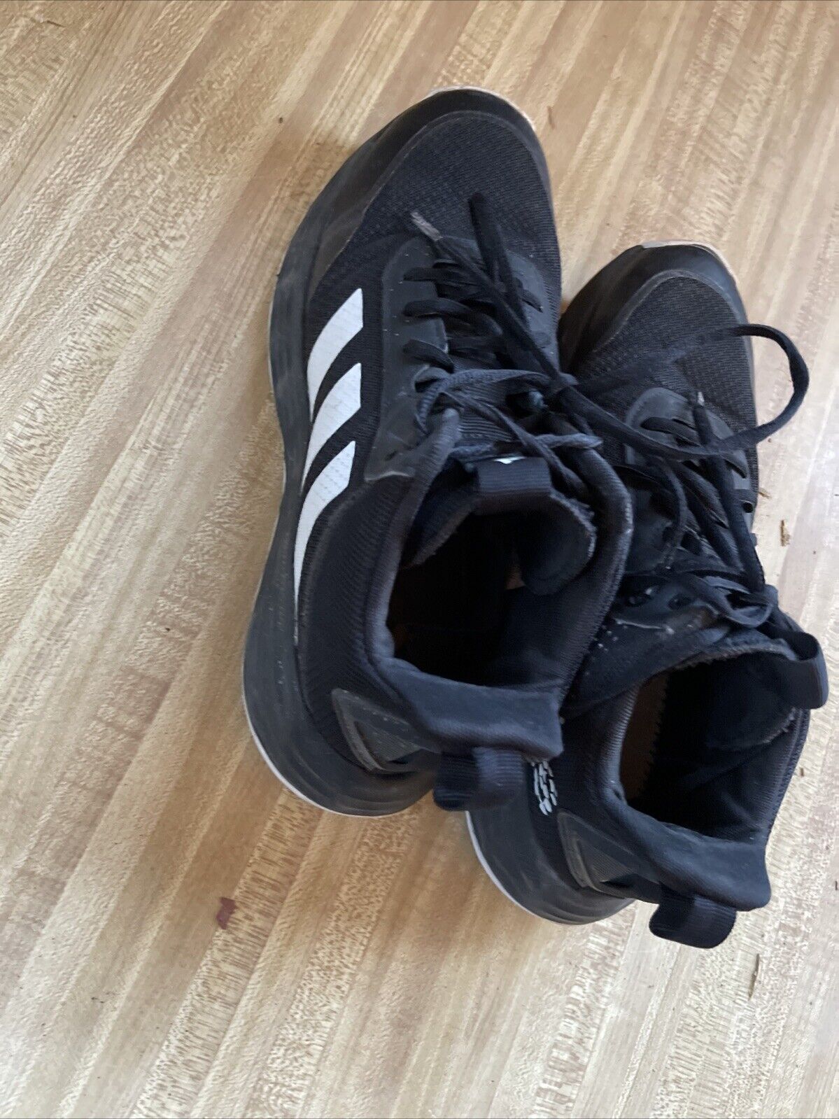 Black adidas lightmotion size 11 athletic shoes with white stripes on wooden floor